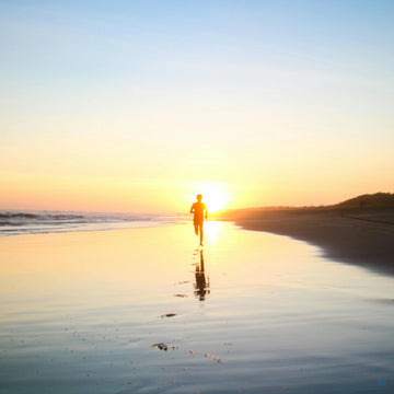hardloper op het strand met zonsondergang