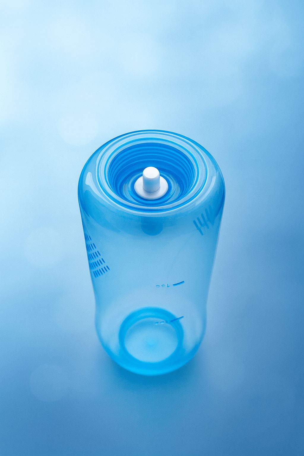 Bovenaanzicht van een transparante blauwe neusdouche-fles met een witte drukknop voor eenvoudige bediening.