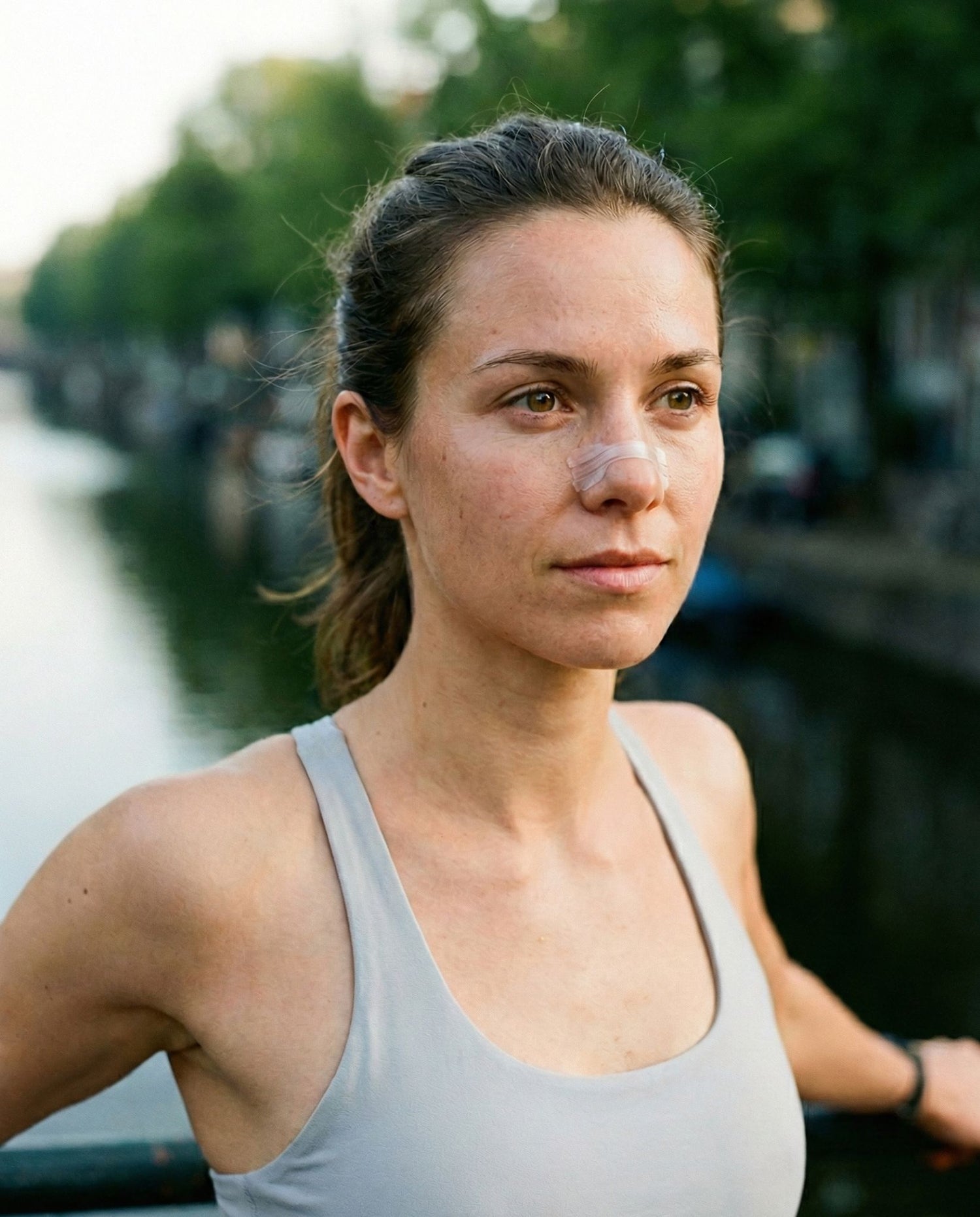 Vrouw die een transparante neusstrip draagt tijdens een wandeling langs het water voor een vrije neusademhaling.