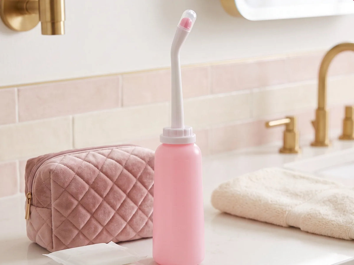 Bouteille bidet sur le lavabo à côté d'une trousse de toilette