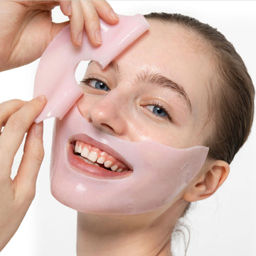 Vrouw die een roze gezichtsmasker voorzichtig van haar gezicht verwijdert